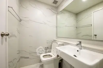 Modern bathroom with sleek white fixtures and elegant marble tiles.