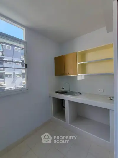 Compact kitchen with open shelving and large window in modern apartment