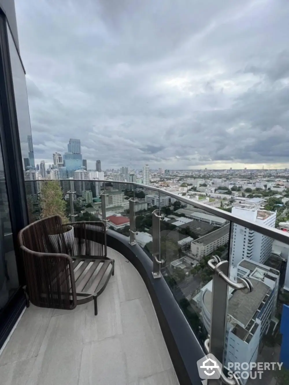 Stunning cityscape view from modern high-rise balcony with sleek glass railing.