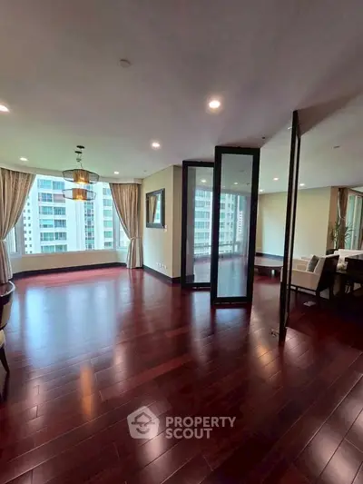 Spacious modern living room with hardwood floors and city view, perfect for urban living.