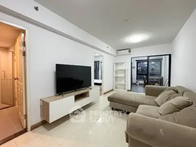 Spacious living room with modern sofa and TV, open layout leading to bedroom, ideal for comfortable living.