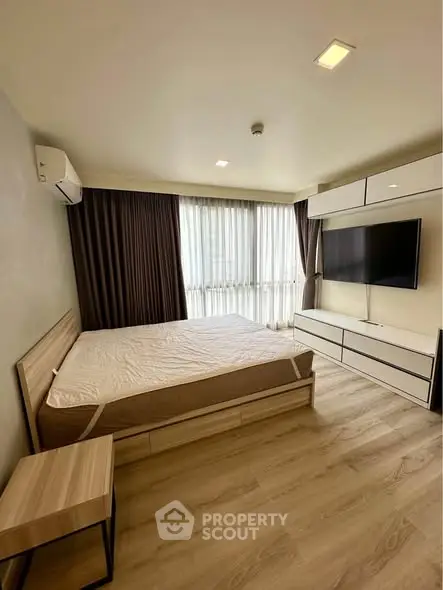 Modern bedroom with large window, wooden flooring, and wall-mounted TV in a stylish apartment.