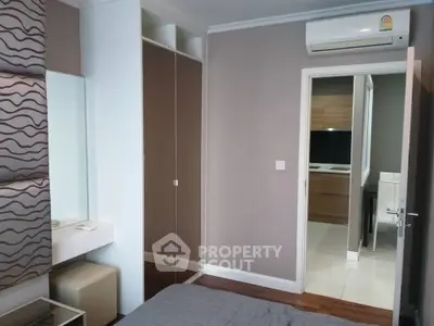 Modern bedroom with built-in wardrobe and air conditioning, featuring a glimpse into a stylish kitchen.