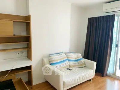 Cozy living room with white sofa and wooden shelves, featuring natural light from large window.