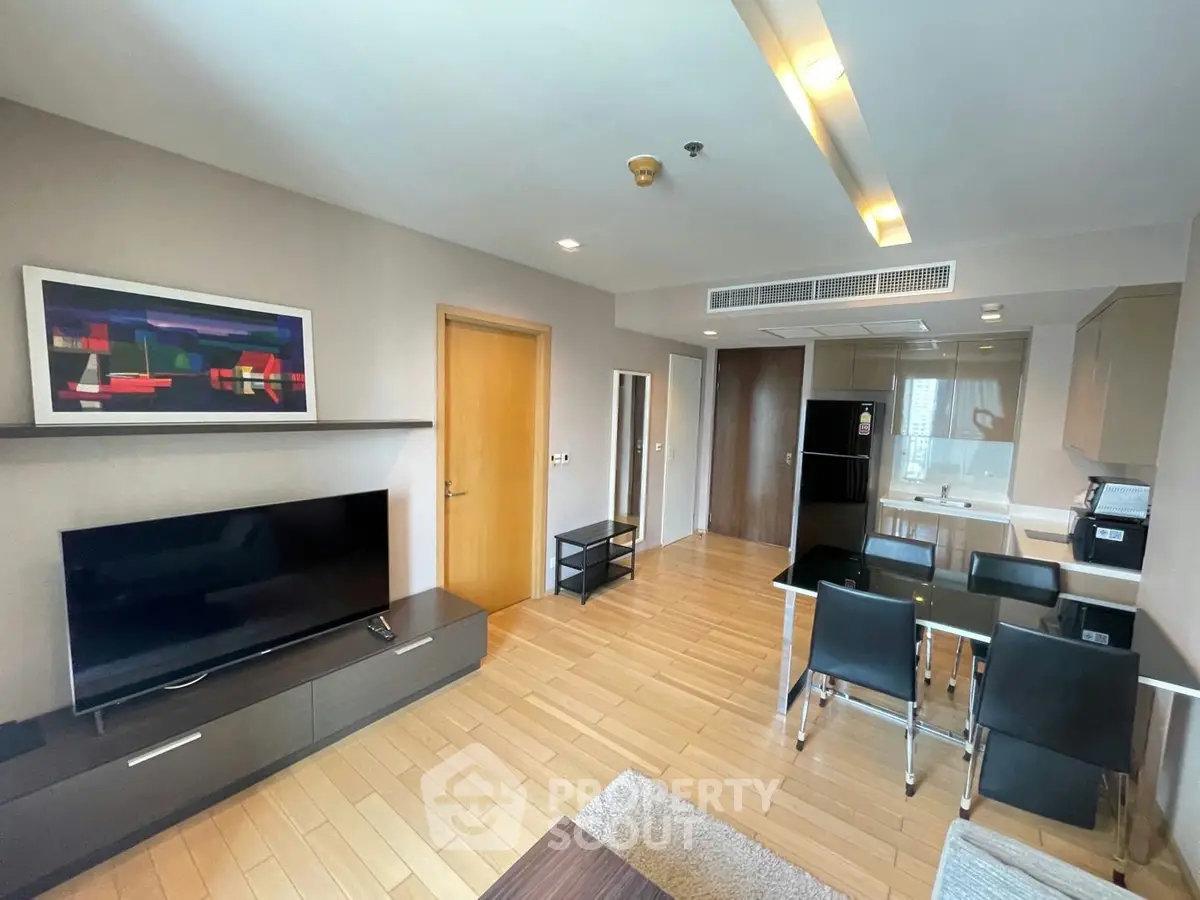 Modern open-plan living room with sleek kitchen and dining area, featuring stylish decor and ample natural light.