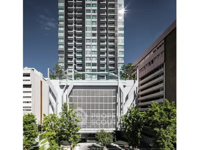 Modern high-rise building with sleek design and lush greenery in urban setting.