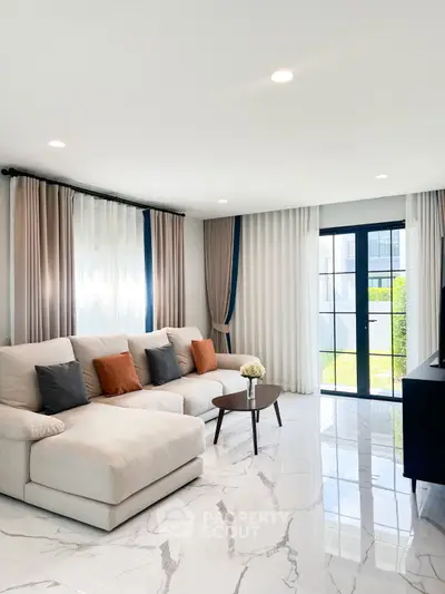 Modern living room with elegant sofa, marble flooring, and large windows for natural light.