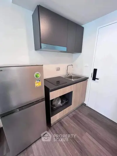 Modern compact kitchen with sleek cabinets and stainless steel appliances in a stylish apartment.