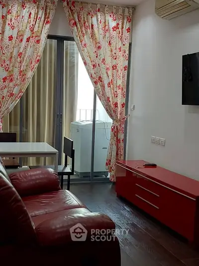 Cozy living room with floral curtains, red leather sofa, and modern TV setup.