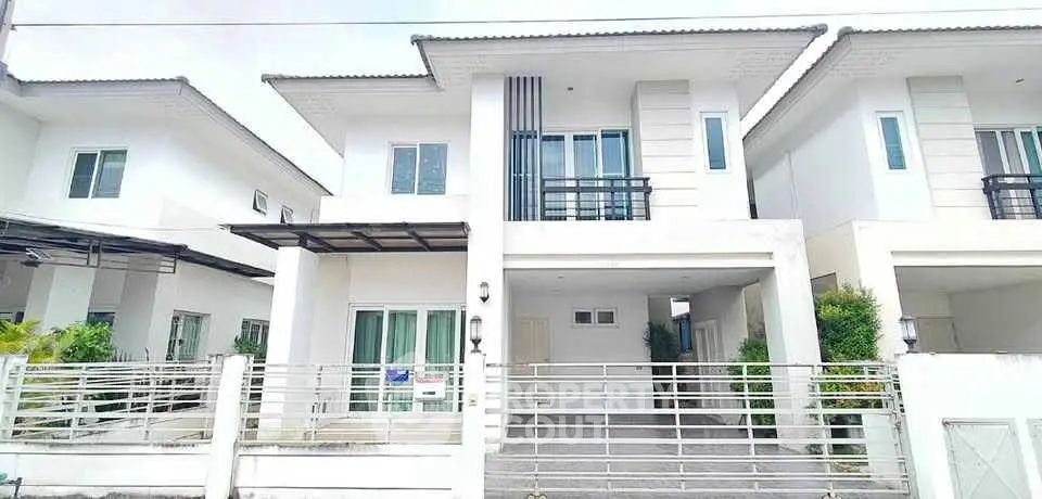Modern two-story white house with balcony and gated driveway in a suburban neighborhood.