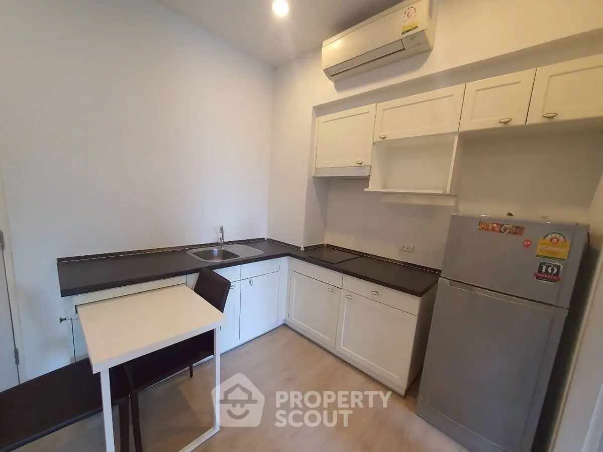 Modern kitchen with sleek design, featuring white cabinets and compact dining area.