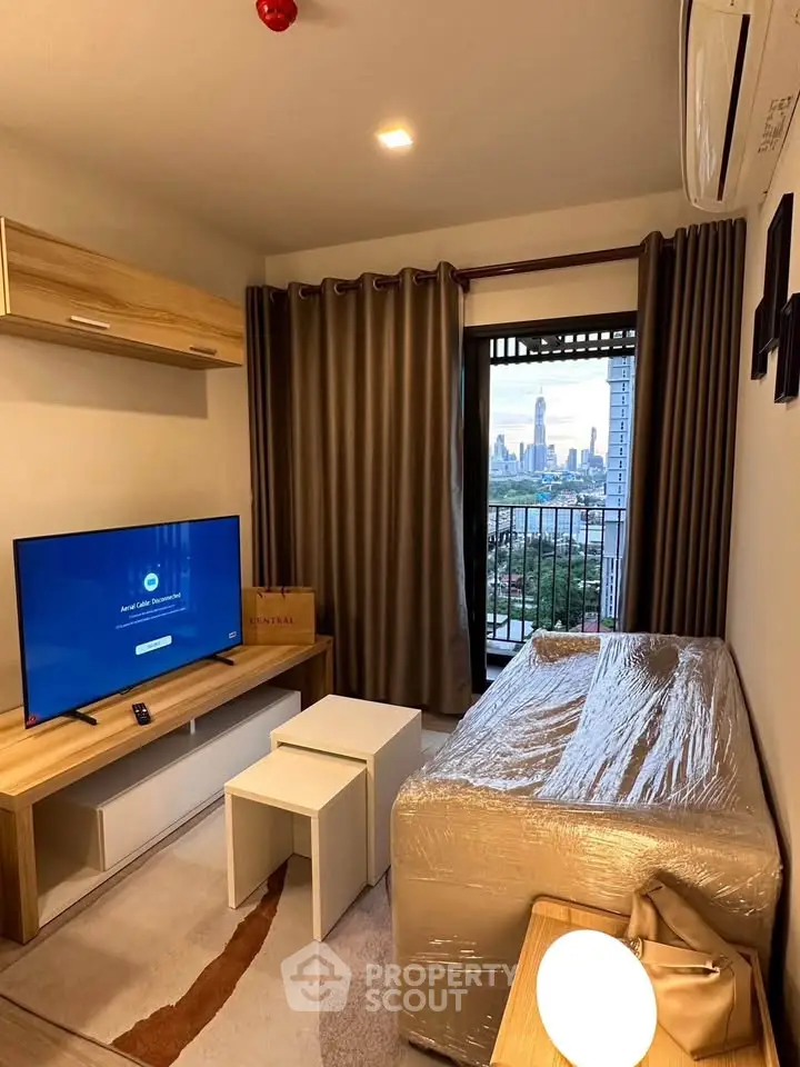 Cozy living room with city view, modern furniture, and large TV, perfect for relaxation.