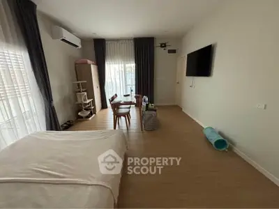 Spacious bedroom with modern decor and large window for natural light.