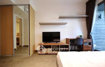 Modern bedroom with TV and desk, featuring sleek design and ample natural light.