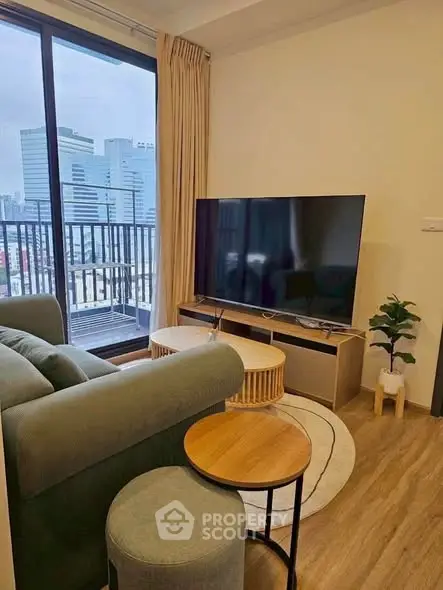 Modern living room with large TV and city view balcony in high-rise apartment.