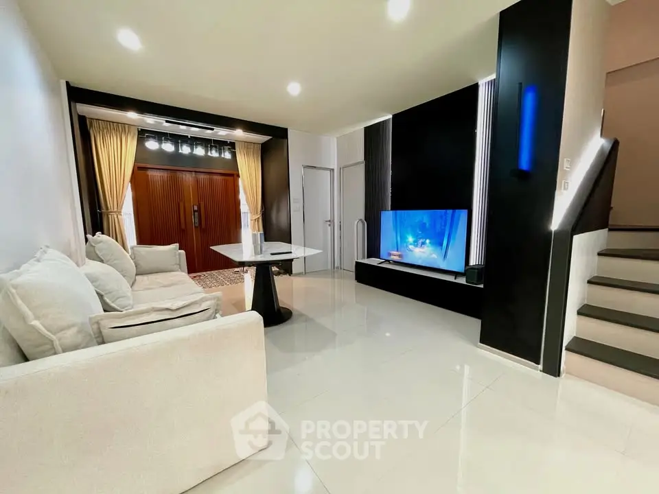 Modern living room with sleek design, featuring a cozy sofa, stylish lighting, and a flat-screen TV.