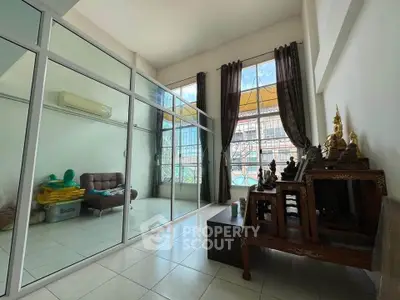 Spacious living room with glass partition and high ceiling, featuring modern decor and ample natural light.