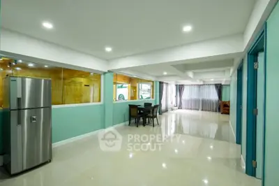 Spacious open-plan living area with modern kitchen and dining space, featuring sleek appliances and ample natural light.