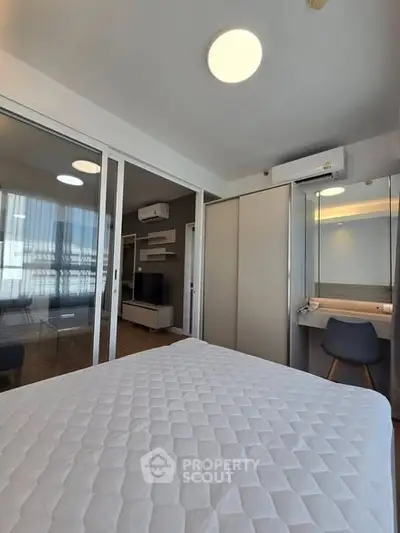Modern bedroom with sliding glass doors and built-in closet, featuring a cozy workspace and air conditioning.