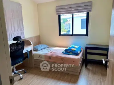 Cozy bedroom with natural light, featuring a single bed, study desk, and modern chair, perfect for a student or professional.
