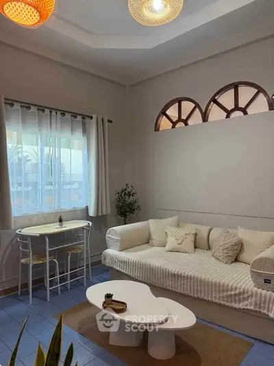 Charming living room with cozy sofa, stylish coffee table, and natural light through arched windows.