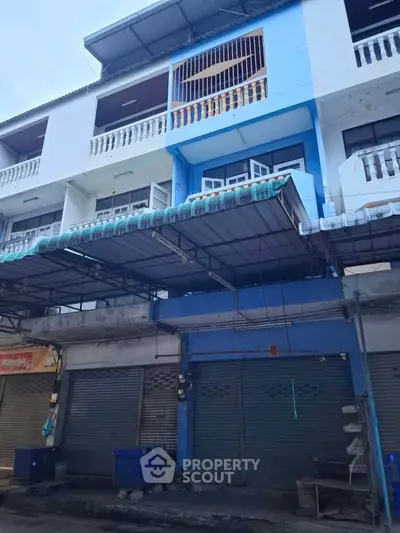 Three-story commercial building with blue accents and closed shutters, ideal for business opportunities.
