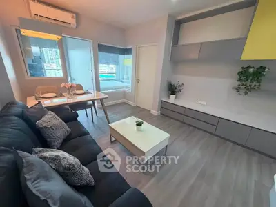 Modern living room with sleek furniture and large windows offering city views.