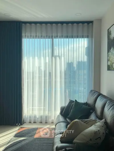 Cozy living room with leather sofa and large window with city view.