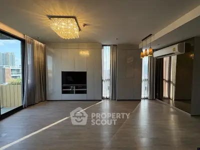 Spacious modern living room with elegant lighting and large windows offering city views.