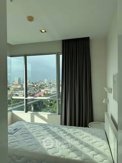 Cozy bedroom with panoramic city view and large windows, perfect for urban living.