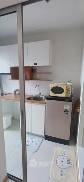 Compact kitchen with modern appliances and sliding glass door in cozy apartment.