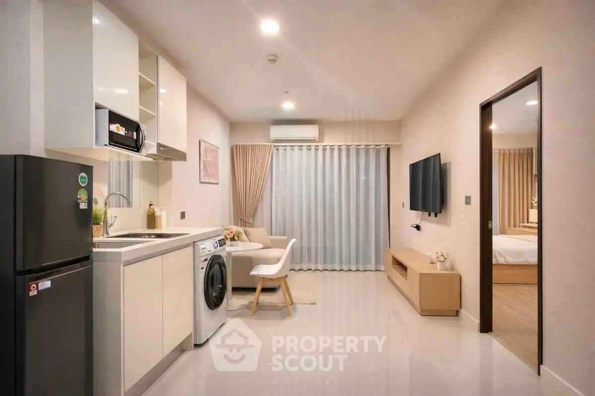 Modern open-plan living room with kitchen and bedroom view, featuring sleek appliances and elegant decor.