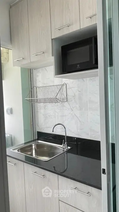 Modern compact kitchen with sleek cabinetry and built-in microwave