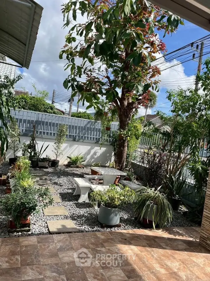 Charming garden patio with lush greenery and stone pathway, perfect for outdoor relaxation.
