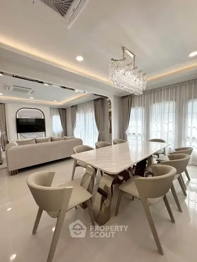 Luxurious open-plan living and dining area with elegant chandelier and modern furniture.