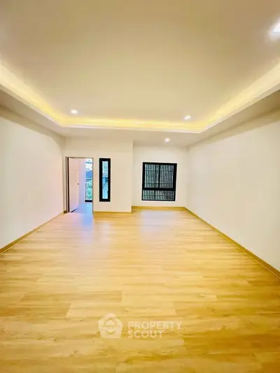 Spacious empty room with wooden flooring and recessed lighting, ideal for customization.