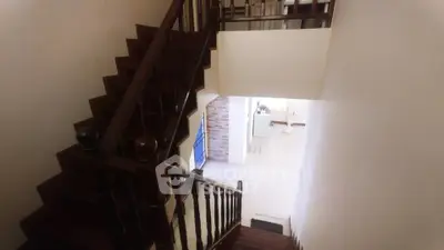 Elegant staircase with wooden railing leading to a bright living area