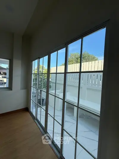 Spacious room with large glass doors opening to a private patio, offering abundant natural light.