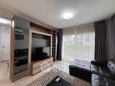Modern living room with sleek furniture and large window offering natural light.