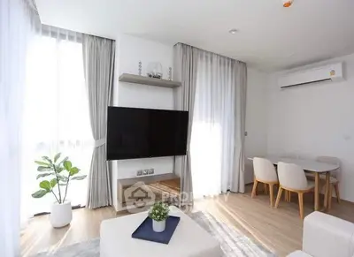 Modern living room with large TV, stylish furniture, and natural light.