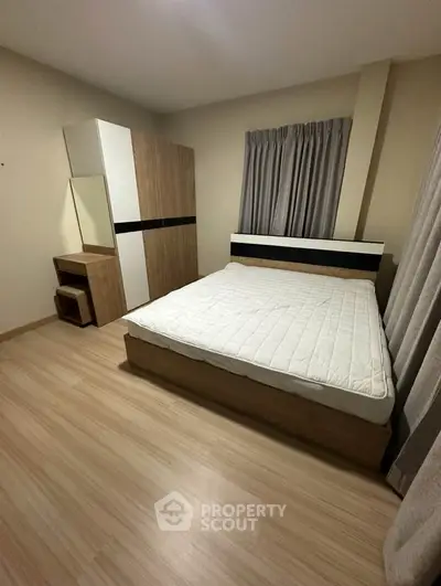 Spacious bedroom with modern wooden furniture and large window for natural light.