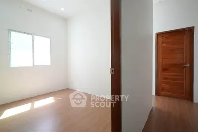 Spacious empty room with wooden flooring and natural light, ideal for customization.
