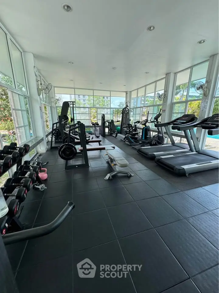 Spacious modern gym with state-of-the-art equipment and large windows offering scenic views.