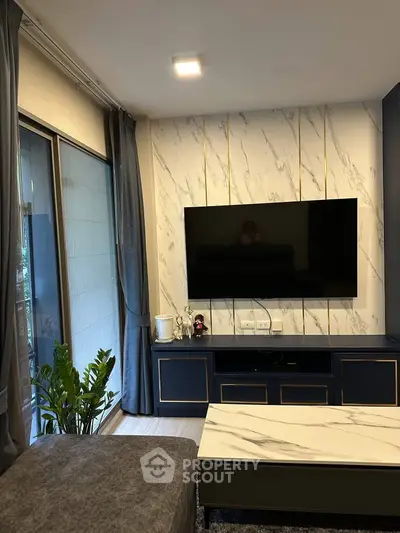 Modern living room with stylish decor and large TV, featuring elegant marble accents and cozy seating.