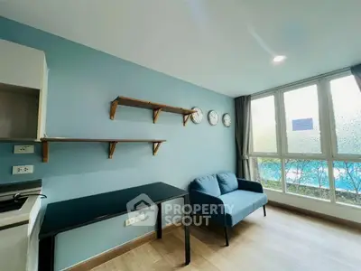 Modern living room with blue sofa, wall shelves, and large windows offering natural light.
