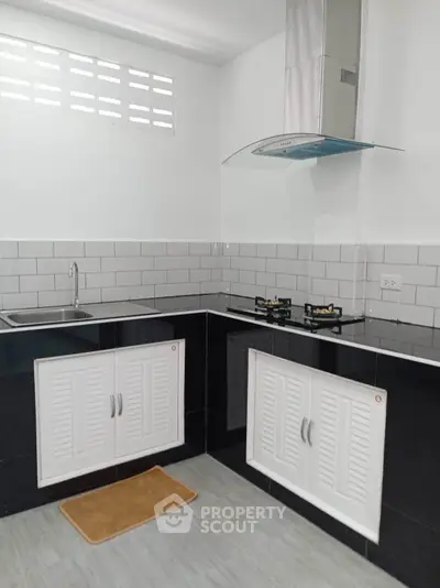 Modern kitchen with sleek black and white design, featuring gas stove and stylish backsplash.