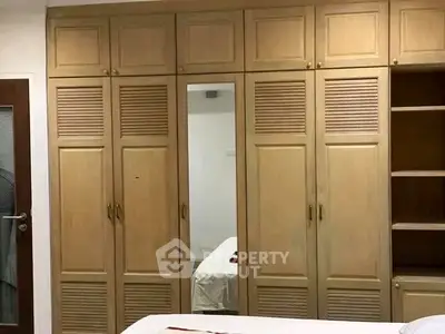 Spacious bedroom with built-in wooden wardrobes and mirror