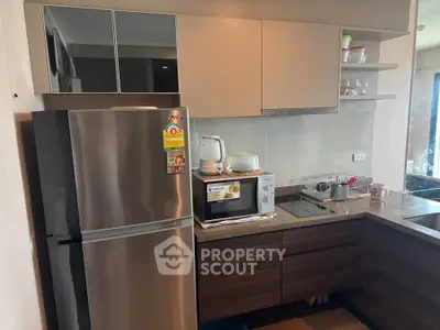 Modern kitchen with sleek cabinets, stainless steel fridge, and built-in microwave in a cozy apartment.