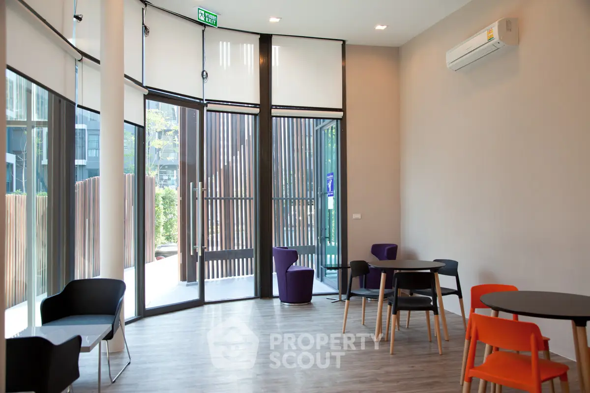 Modern common area with stylish furniture and large windows in a contemporary building.