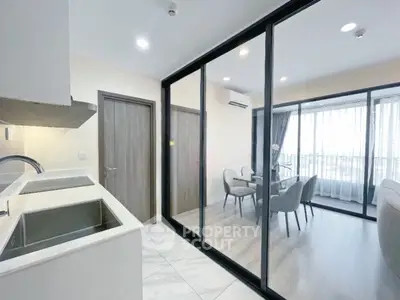 Modern open-layout kitchen and dining area with glass partition and natural light